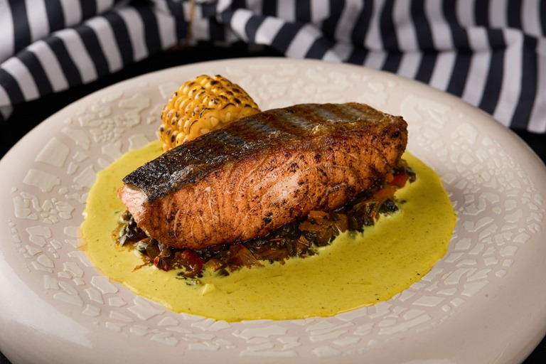 Ruvia Restaurant - thick grilled salmon fillet with grill marks, served over sauce with grilled corn