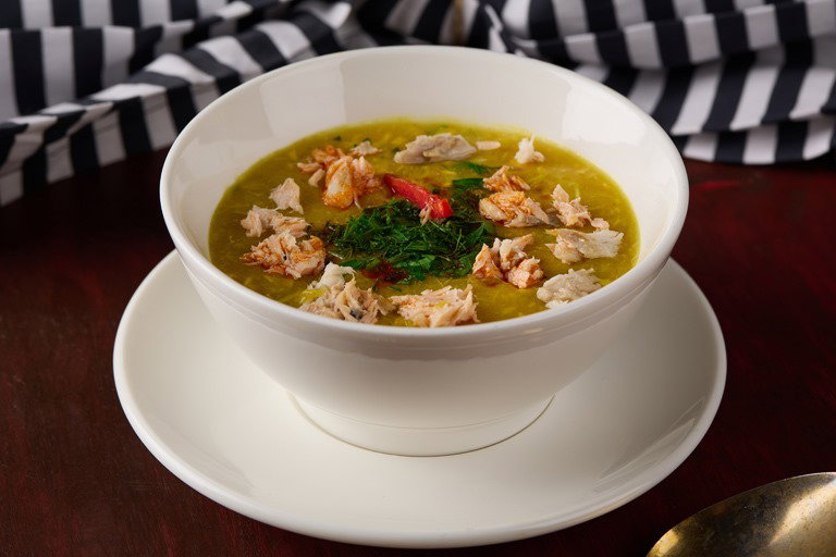 Ruvia Restaurant - Turkish fish soup (balik corbasi) with pieces of fish and herbs in a white bowl