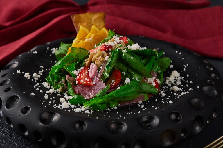 Ruvia Restaurant - roka salatasi, a rocket salad dressed with lemon and olive oil on a dark plate